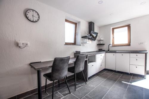 a kitchen with a table and chairs and a clock on the wall at Old Mill House in Bohinj