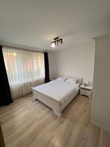 Schlafzimmer mit einem weißen Bett und Holzboden in der Unterkunft Star Apartments in Baia Mare