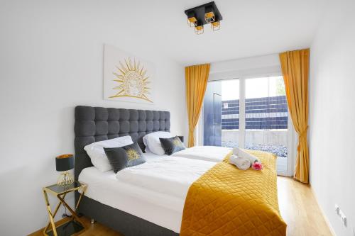 ein Schlafzimmer mit einem großen Bett und einer gelben Decke in der Unterkunft CT-GOLD Apartments - Villach Malina - nahe Atrio und Therme in Villach