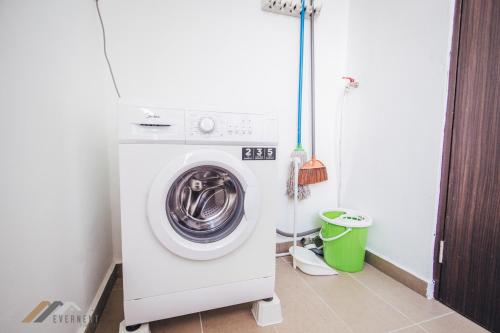a washing machine in a bathroom with a green trash can at Serene Heights by Evernent in Miri