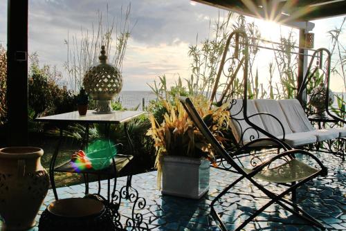 a patio with a chair and a table and the ocean at BOUTIQUE VILLA con accesso privato alla spiaggia in Caronia