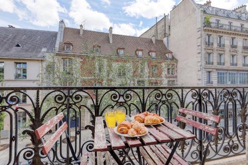 une table en bois avec une assiette de nourriture sur un balcon dans l'établissement Cosy Parisian 1Bdr Flat - Prime Location le Marais, à Paris
