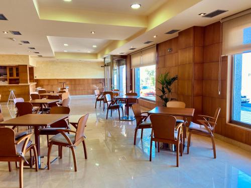 a restaurant with wooden tables and chairs and windows at Duerming Areas Playa Hotel in Sanxenxo