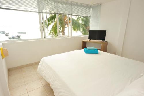 a bedroom with a white bed and a window at The Beach House - West Coast Mauritius in Rivière Noire