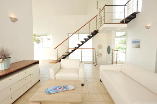 a living room with a white couch and stairs at The Beach House - West Coast Mauritius in Rivière Noire