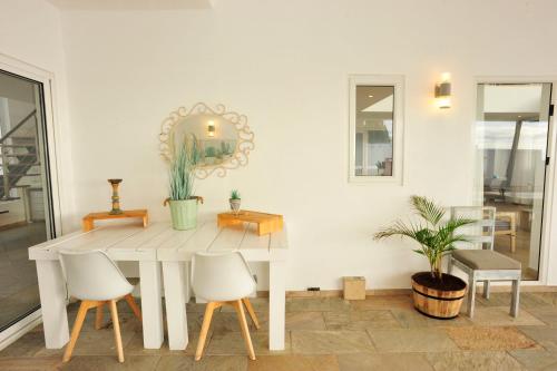 a white dining room table with white chairs and a mirror at The Beach House - West Coast Mauritius in Rivière Noire