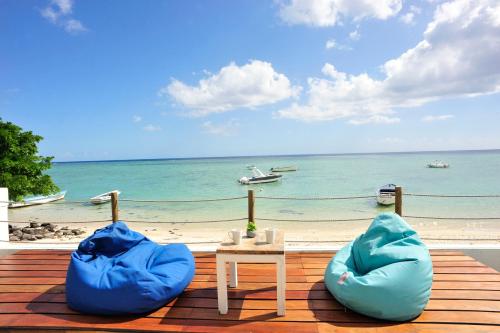 two blue bean bags and a table and a beach at The Beach House - West Coast Mauritius in Rivière Noire