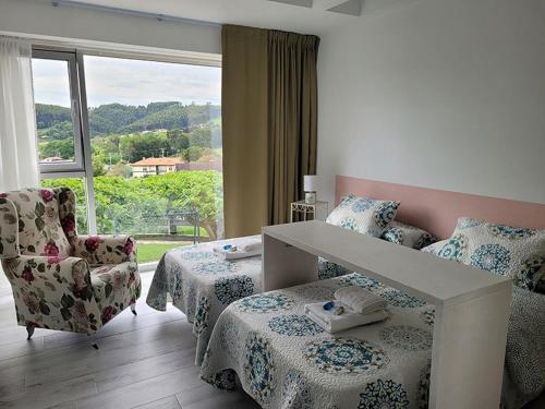 1 dormitorio con 2 camas, silla y ventana en La Casuca de Mamina en Miengo