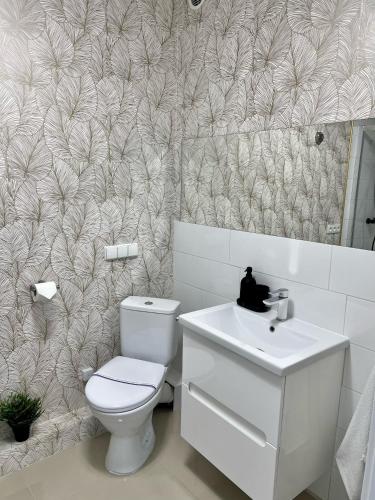 a bathroom with a white toilet and a sink at Zielone Apartamenty Katowice Chorzów in Chorzów