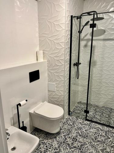 a white bathroom with a toilet and a shower at Zielone Apartamenty Katowice Chorzów in Chorzów