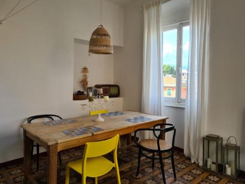 a dining room table with yellow chairs and a window at Casetta in Centro, a Chiavari, by Cinqueterrecoast in Chiavari
