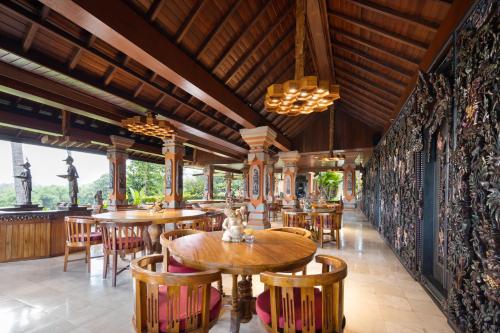 a restaurant with tables and chairs and a wall of windows at Swan Paradise A Pramana Experience in Gianyar