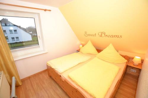 um pequeno quarto com uma cama com lençóis amarelos e uma janela em Enjoy-Sylt-1 em Westerland