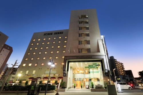 ein hohes Gebäude mit einem beleuchteten Gebäude in der Unterkunft Atsugi Urban Hotel in Atsugi