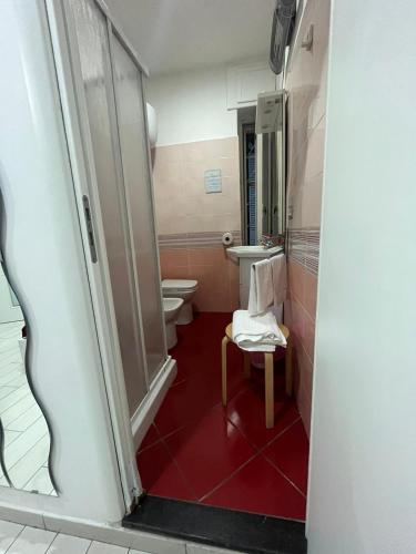 a bathroom with a toilet and a sink and a chair at Family Room in Portici