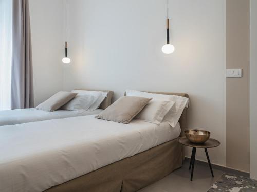 two beds in a bedroom with white walls and a table at Living u HomeSuites in Lecce