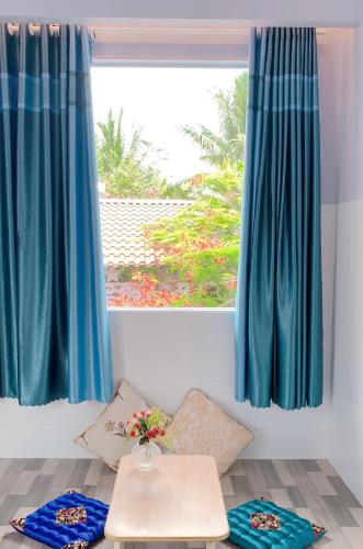 a room with blue curtains and a table and a window at Khách sạn SAKÊ Tiền Giang in Chợ Gạo