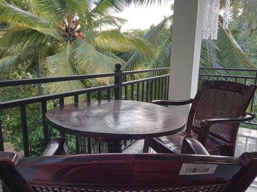 a table and chairs on a porch with a palm tree at Jungle Village Homestay in Pinnawala