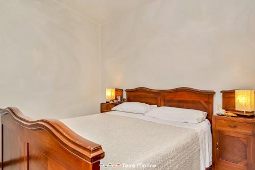 Schlafzimmer mit einem Bett mit weißer Bettwäsche und Holzmöbeln in der Unterkunft Ca da Derna in Riomaggiore