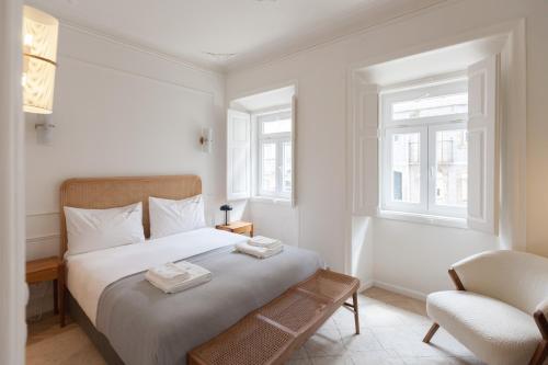 a white bedroom with a bed and a chair at FLH Lapa Apartment with Interior Pateo in Lisbon