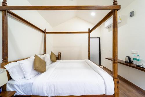 a bedroom with a wooden canopy bed with white sheets at The Ayali Riverside Resort in Rishīkesh