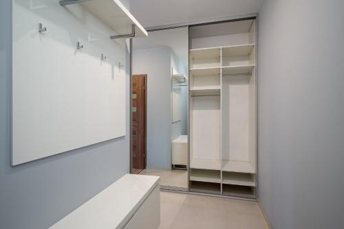 vestidor con armarios blancos y espejo en Apartament City Life Złote Łany en Bielsko-Biala