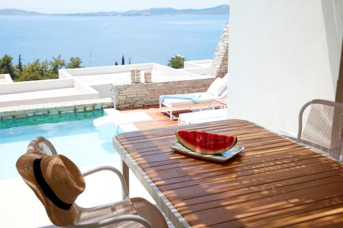 a watermelon sitting on a wooden table next to a pool at Eagles Villas - Small Luxury Hotels of The World in Ouranoupoli