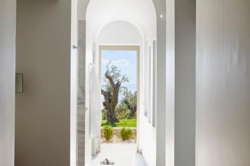 an archway leading into a white hallway with a tree at Eagles Villas - Small Luxury Hotels of The World in Ouranoupoli