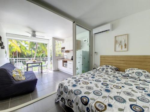 um quarto com uma cama e um sofá e uma varanda em Studio CocoCaraïbes Anse des Rochers vue mer - piscine em Belle-Allée