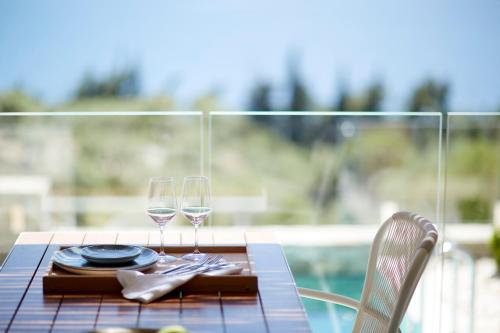 a table with two glasses of wine on a table at Eagles Villas - Small Luxury Hotels of The World in Ouranoupoli