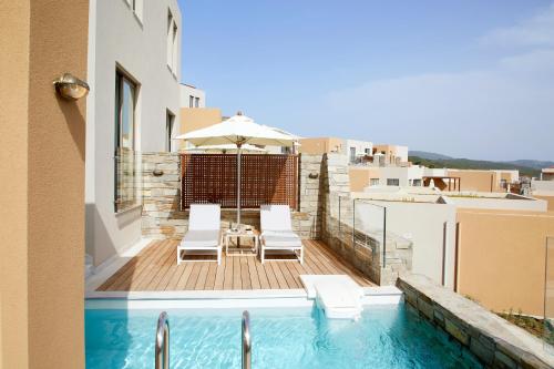 a balcony with a swimming pool with chairs and an umbrella at Eagles Villas - Small Luxury Hotels of The World in Ouranoupoli