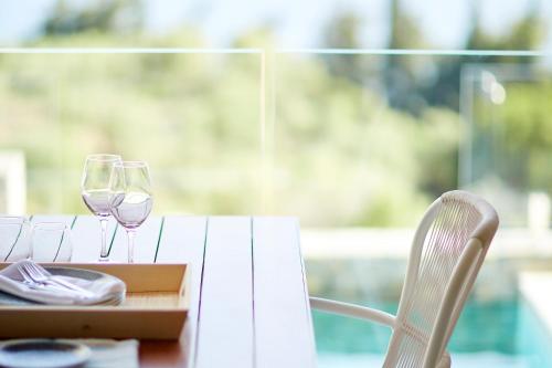 a table with two wine glasses and a box on it at Eagles Villas - Small Luxury Hotels of The World in Ouranoupoli