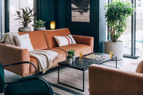 ein orangefarbenes Sofa im Wohnzimmer mit Topfpflanzen in der Unterkunft Chic Apartments and Studios at The Point in Aberdeen in Aberdeen
