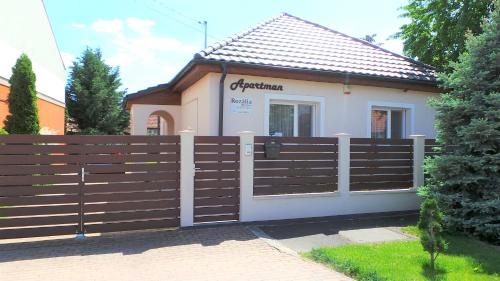 una casa con una valla de madera delante de ella en Rozalia Apartman, en Gyula