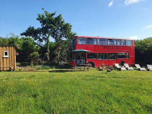 um autocarro vermelho de dois andares estacionado num campo em Double Decker Bus on an Alpaca farm sleeps 8, 5 mins drive to Dartmoor em Bovey Tracey