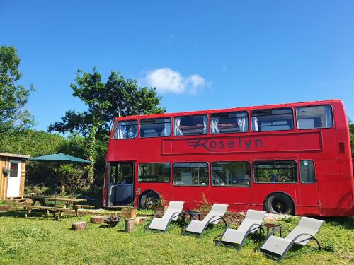 um autocarro vermelho de dois andares estacionado ao lado das cadeiras em Double Decker Bus on an Alpaca farm sleeps 8, 5 mins drive to Dartmoor em Bovey Tracey