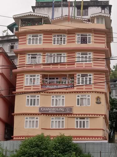 Un grand bâtiment orange avec un panneau. dans l'établissement Khandroling Hotel, à Gangtok