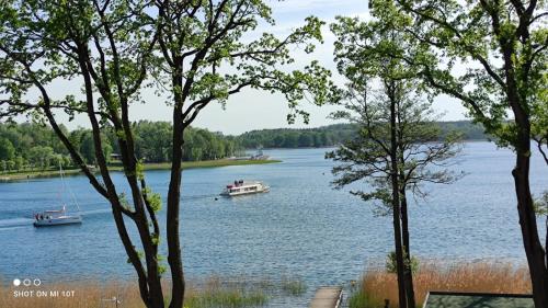 two boats on a lake with trees in the foreground at LOFT STRANDA in Giżycko