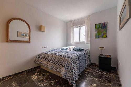 um quarto com uma cama, um espelho e uma janela em Casa Annelise em Fuengirola