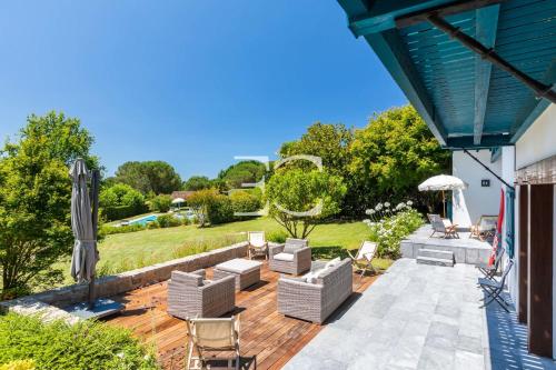 een terras met stoelen en een parasol bij Easy Clés- Villa on the golf Pool AC in Arcangues