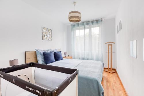 um quarto branco com uma cama com almofadas azuis em Cosy appartement Proche Disneyland Paris em Montévrain