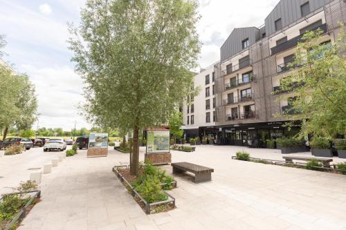 a courtyard with a tree and benches and a building at Cosy appartement Proche Disneyland Paris in Montévrain
