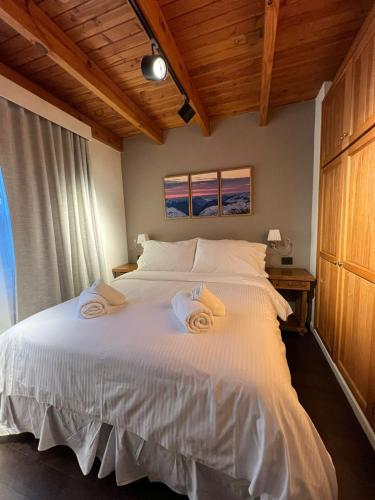 a bedroom with a white bed with towels on it at Apart Hotel Agua Escondida in San Martín de los Andes