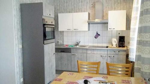 a kitchen with white cabinets and a table and chairs at Rügen Fewo 31 in Göhren