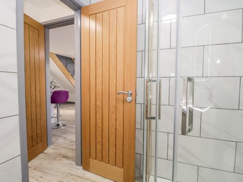 a wooden door in a bathroom with a glass shower at The Annex in Ulverston