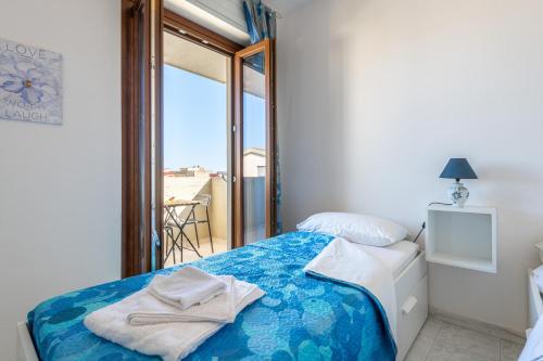 a bedroom with a bed with blue sheets and a window at La Casa del Sole in Selargius