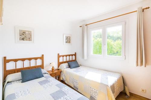 two beds in a room with a window at Villa Sol y Sombra by Escape Home in Son Bou