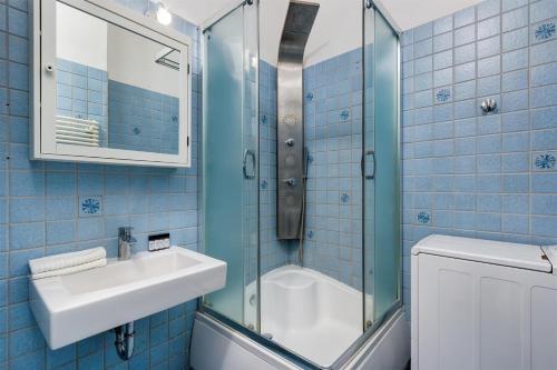 a blue tiled bathroom with a sink and a shower at Liberty Square Apartment in Budapest
