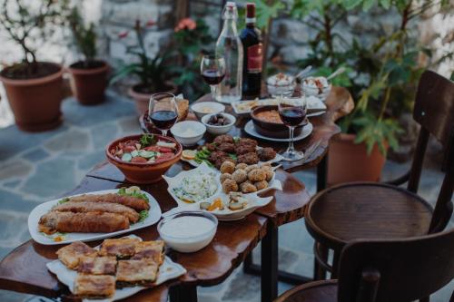 Una mesa de madera cubierta con platos de comida y copas de vino. en Tradita e Beratit, en Berat