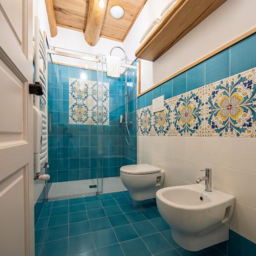 a blue tiled bathroom with a toilet and a sink at Etna Quota Mille Boutique Hotel, Typical Sicilian Food & Wine in Randazzo